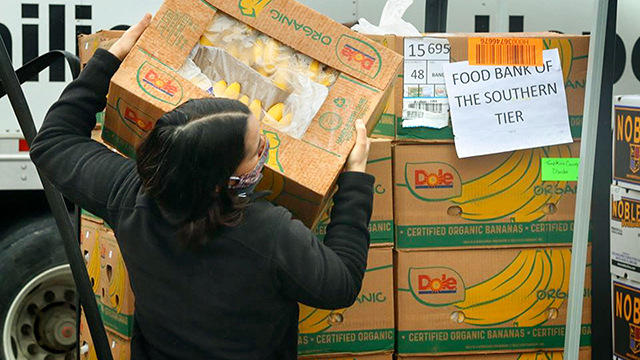 A person loads a box of food at a pantry.