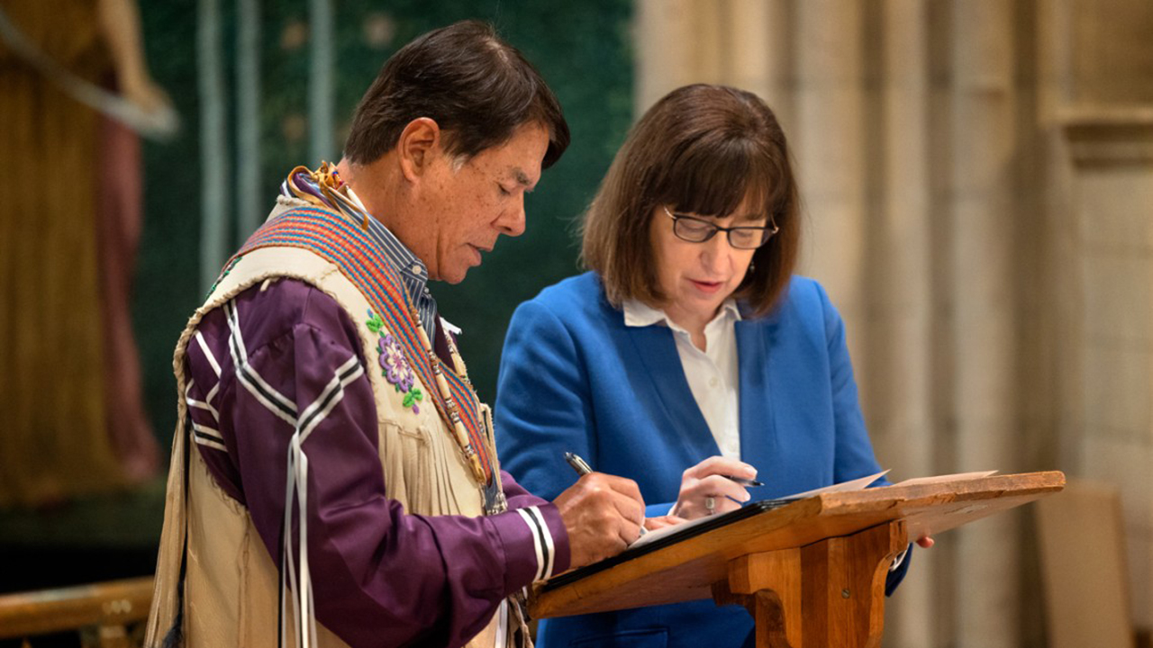 Ray Halbritter, representing the Oneida Indian Nation, and President Martha E. Pollack, sign documents.