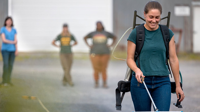 Doctoral student Maria Gannett practices a walking cadence with a sprayer full of water.